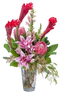 king protea and star gazer pink lilies with red and green accents in vase
