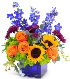 sunflowers adn oragne roses with purple accents in blue cube