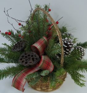 A RUSTIC GRAPEVINE BASKET FILLED WITH FRESH MIXED GREENS ACCENTED WITH LOTUS PODS, BERRIES, CONES, AND FROSTED BRANCHES.