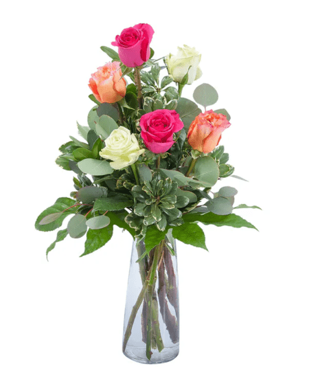 Mixed colors of roses arranged in a clear glass vase.